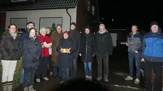 Kirchen-Blasorchester spielt, geleitet von einem Dirigenten, vor einem Holzkreuz.