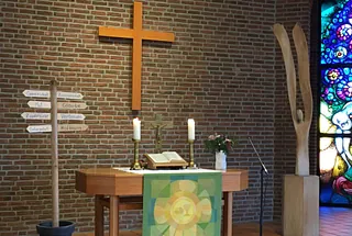 Teelicht brennt in einer Glasvase über kleinen dekorativen Steinen.