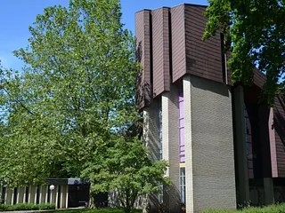 Modernes Kirchengebäude mit Ziegeln, Beton und braunen geometrischen Platten.