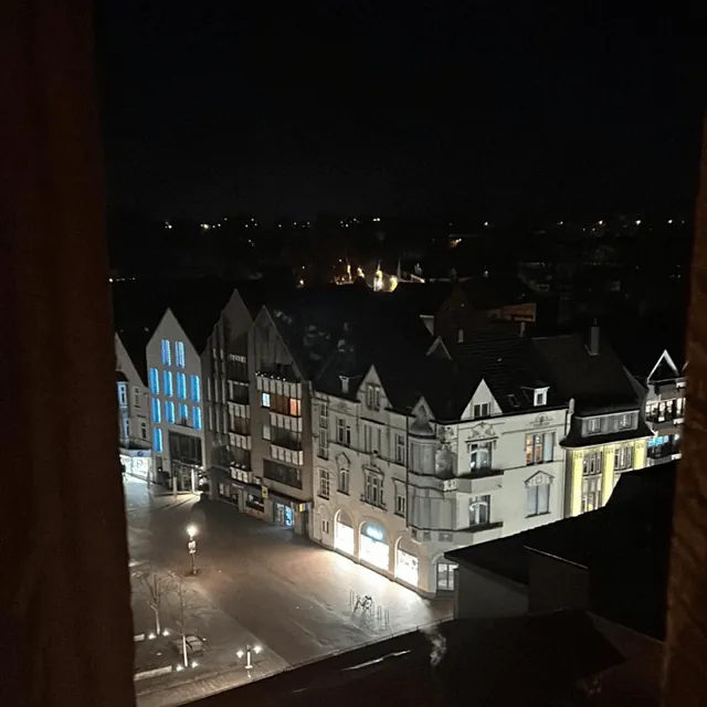 Nachtaufnahme eines leeren Stadtplatzes umgeben von beleuchteten historischen Gebäuden.