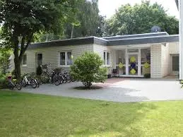 Außenansicht eines modernen eingeschossigen Kindergartens mit abgestellten Fahrrädern.