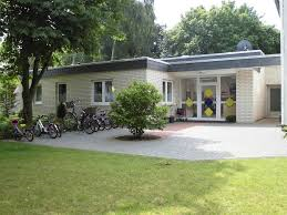 Außenansicht eines modernen eingeschossigen Kindergartens mit abgestellten Fahrrädern.