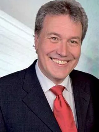 Professionelles Porträt eines Mannes in Anzug, weißem Hemd und knallroter Krawatte.