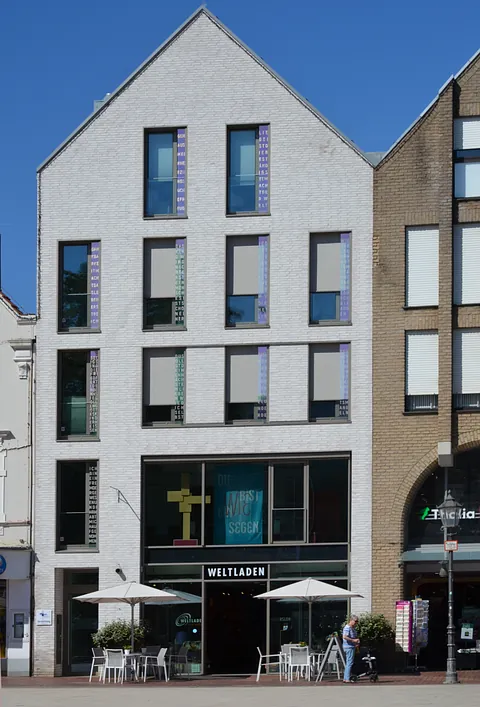 Moderne Backsteinkirche mit braunem Turm und violettem Banner über Freiheit.