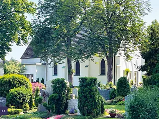 Neugotische Steinkirche mit hohem Turm und Bogenfenstern bei trübem Wetter.