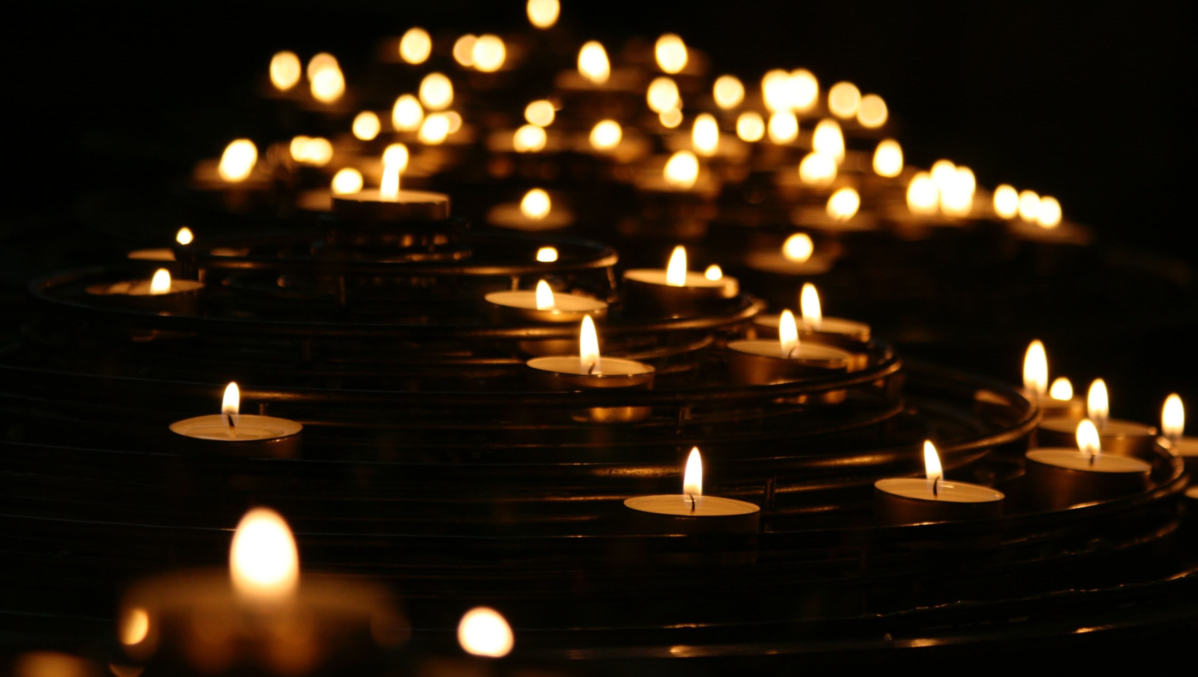 Nahaufnahme von brennenden Votivkerzen in einer Kirche.