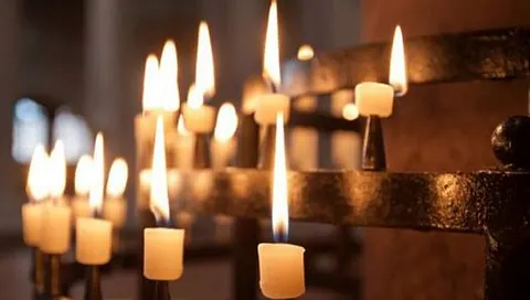 Nahaufnahme von brennenden Votivkerzen in einer Kirche.