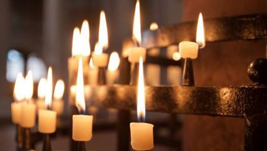 Nahaufnahme von brennenden Votivkerzen in einer Kirche.