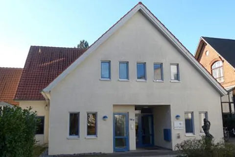 Gemeindezentrum mit weißer Fassade und rotem Ziegeldach.