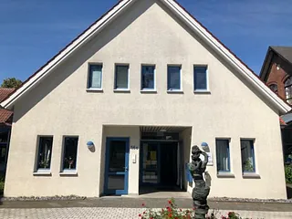 Gemeindezentrum mit weißer Fassade und rotem Ziegeldach.