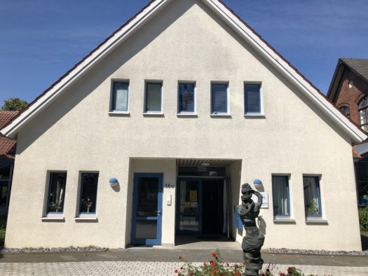 Moderne Backsteinkirche mit braunem Turm und violettem Banner über Freiheit.